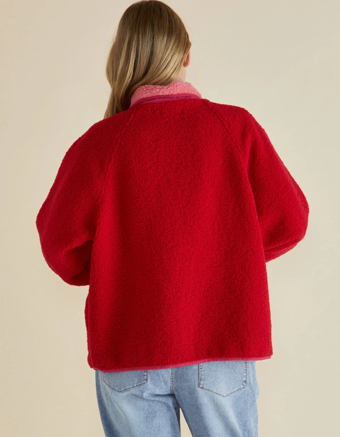 Person wearing a red jacket on a beige background