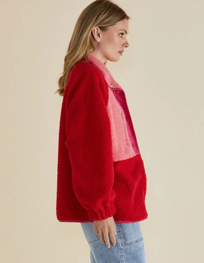 Woman wearing a red jacket with a pink shirt underneath on a beige background