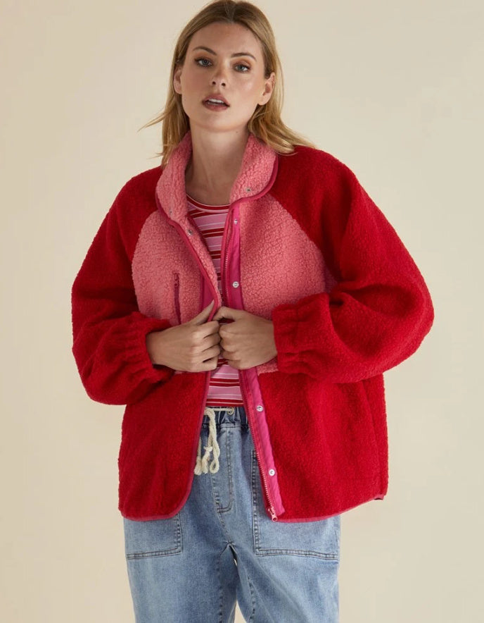 Woman wearing a red jacket with a pink interior on a beige background
