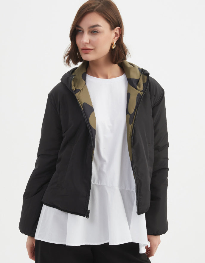 Woman wearing a camouflage olive and black reversible puffer jacket on a white background