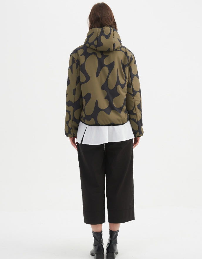 Woman wearing a camouflage olive and black reversible puffer jacket on a white background
