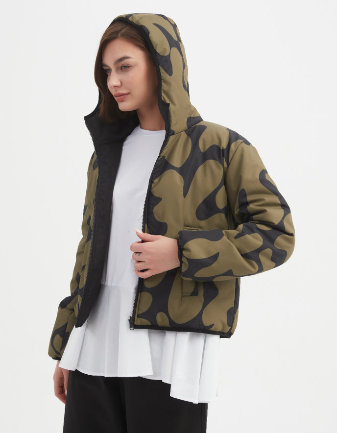 Woman wearing a camouflage olive and black reversible puffer jacket on a white background