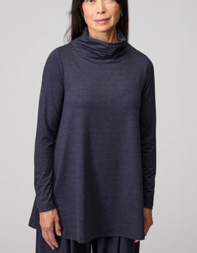 Woman wearing a dark blue long-sleeve top against a plain background