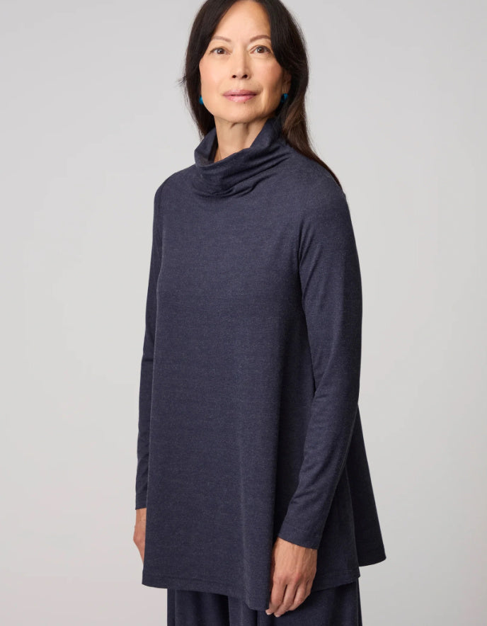 Woman wearing a dark blue long-sleeve top against a plain background