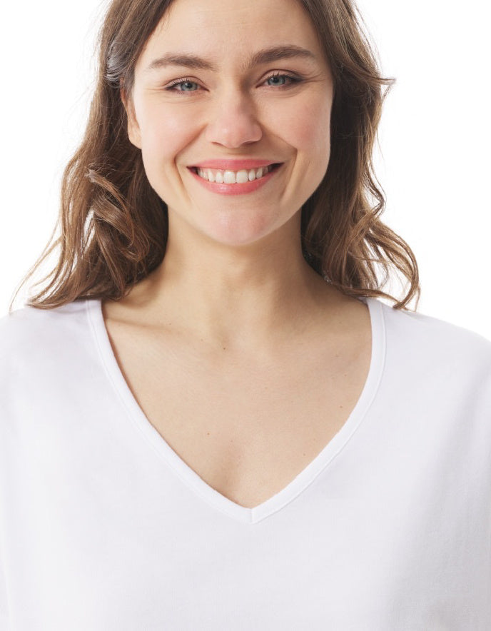 Woman wearing a white V-neck shirt against a plain background