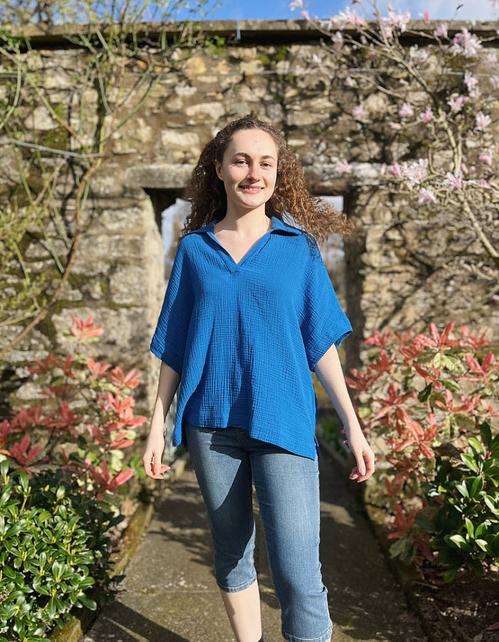loose fit white over the head shirt with V neckline and collar, loose dropped shoulder with wide elbow length sleeve in gauzy cobalt blue cotton