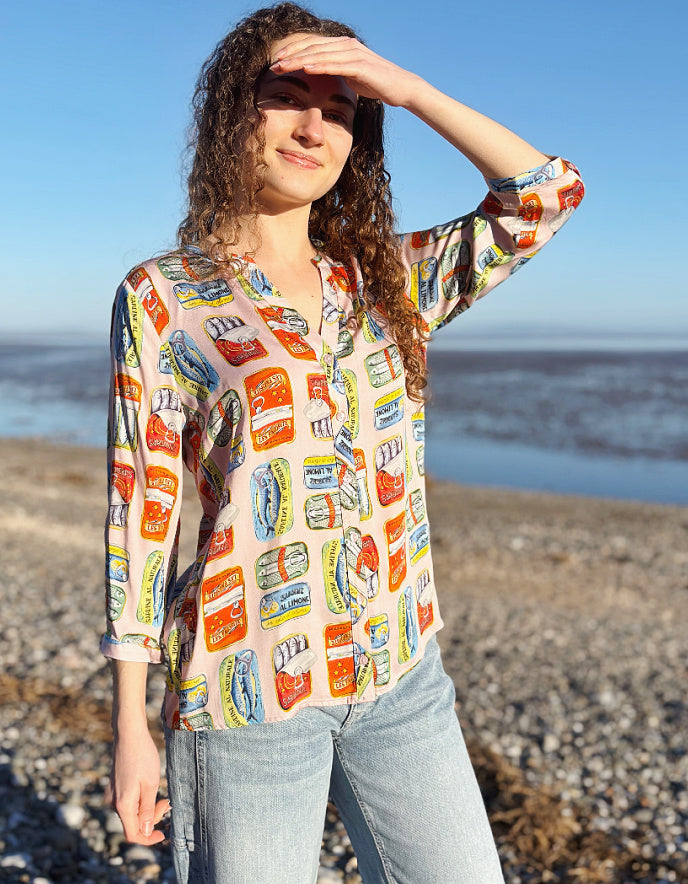 person wearing silk blouse with print of tins of sardines on it