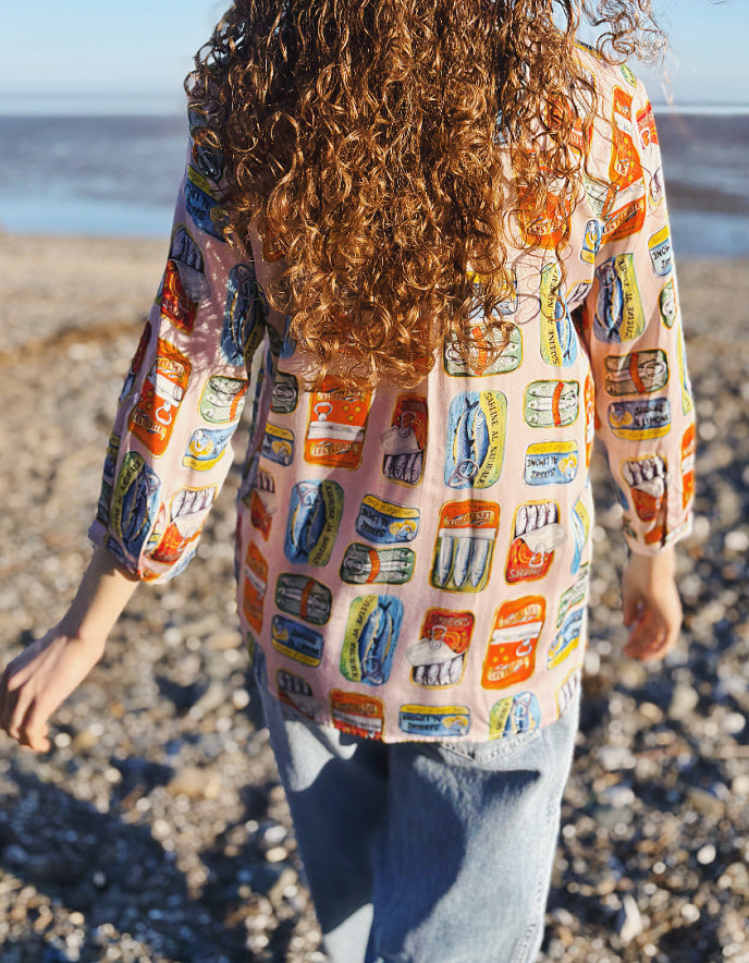 person wearing silk blouse with print of tins of sardines on it