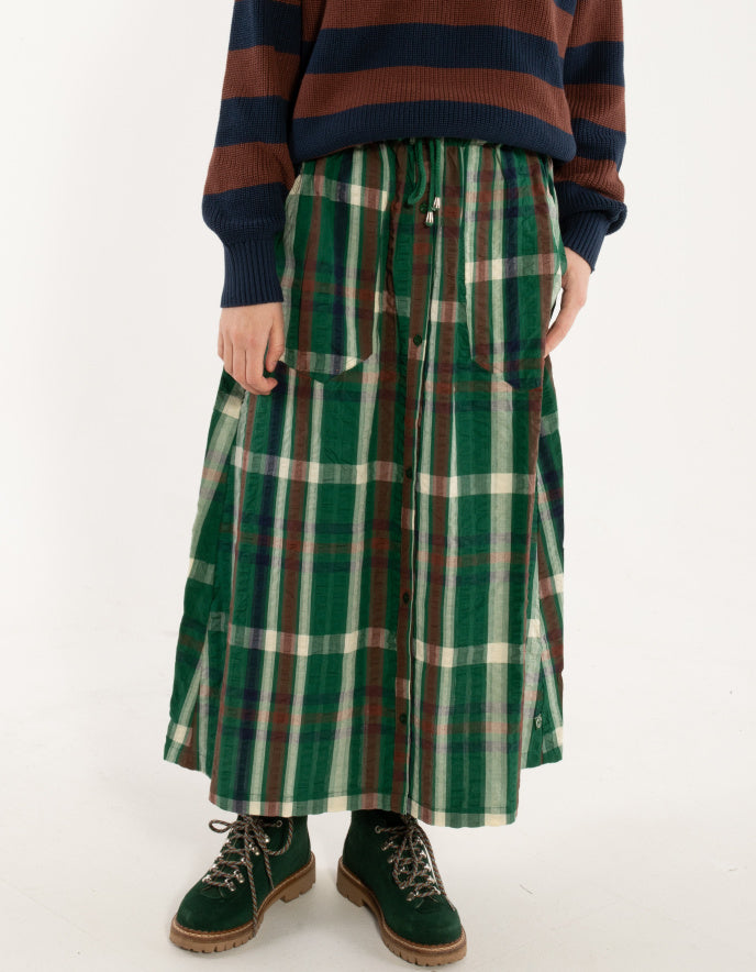 Person wearing a green plaid skirt with a striped sweater on a white background