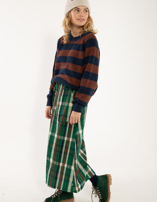 Woman wearing a striped sweater and plaid skirt on a white background