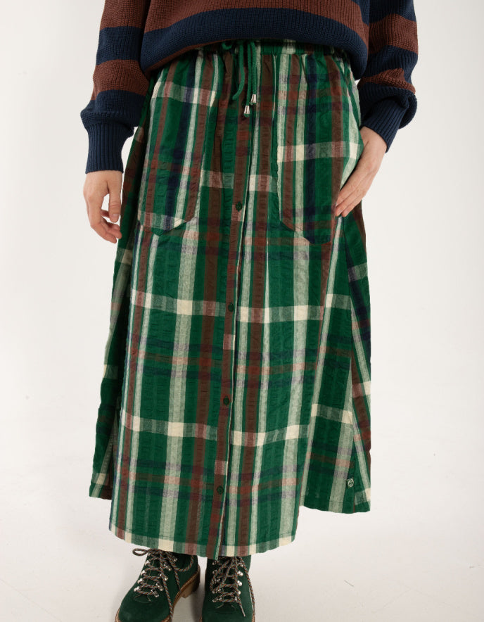 Person wearing a green plaid skirt with a striped sweater on a white background