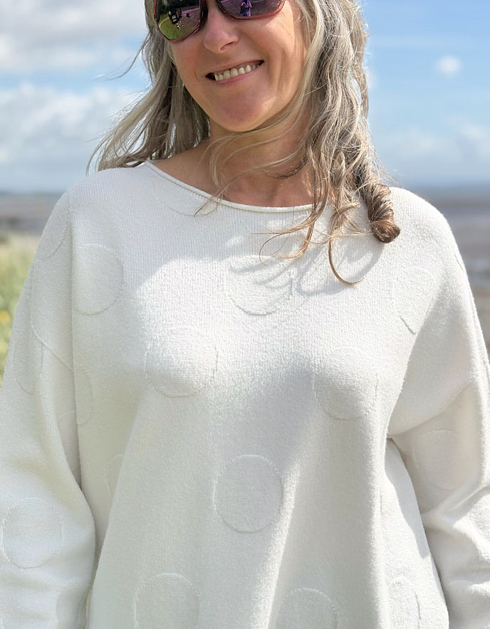 Woman wearing a white sweater with a scenic background