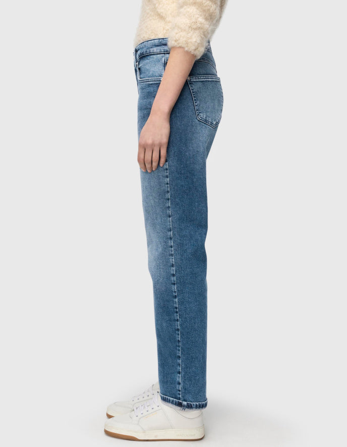 Person wearing blue jeans and a white sweater on a plain background