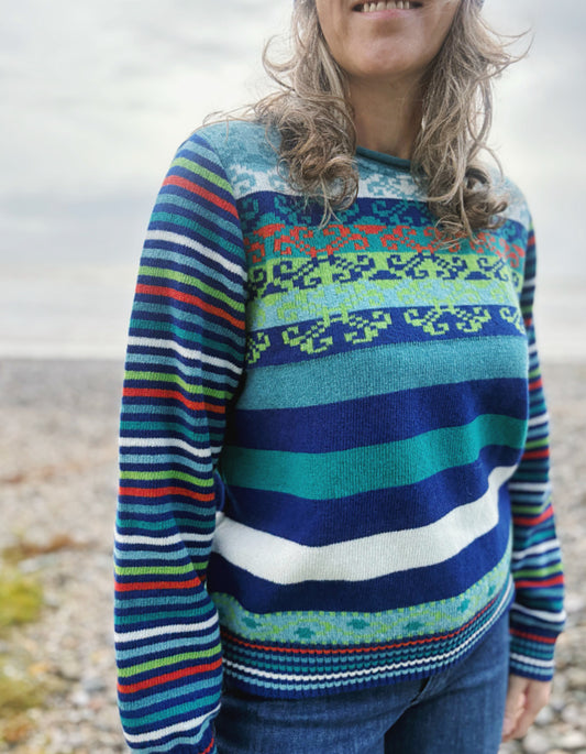 Person wearing a colorful striped sweater on a beach