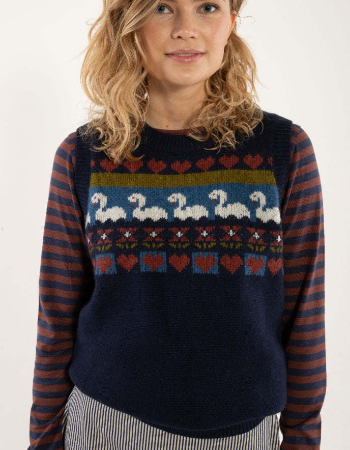 Woman wearing a sweater with a pattern of swans and stripes on a plain background