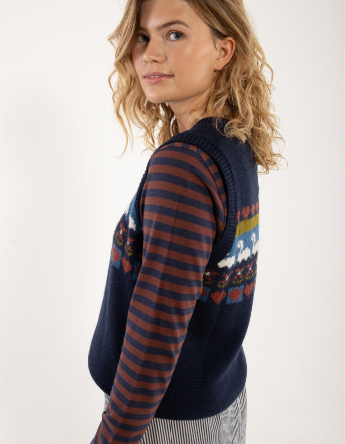 Woman wearing a navy sweater with colorful patterns on a white background