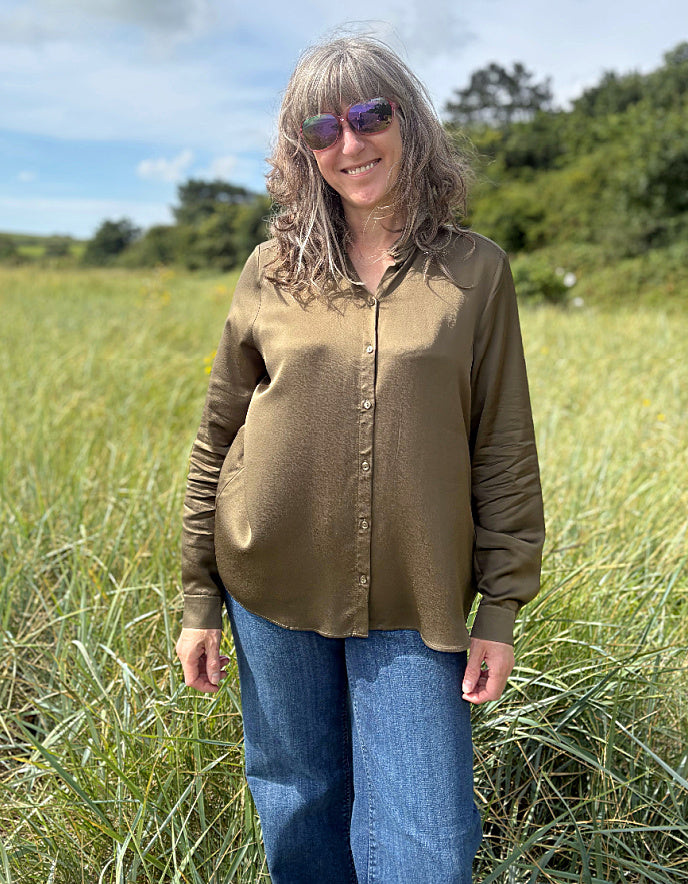 Person wearing a olive silky blouse in a field