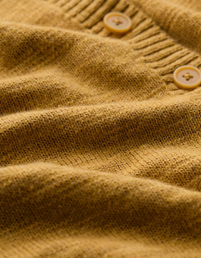 woman wearing ochre yellow coloured cotton linen cardigan with a floral dress