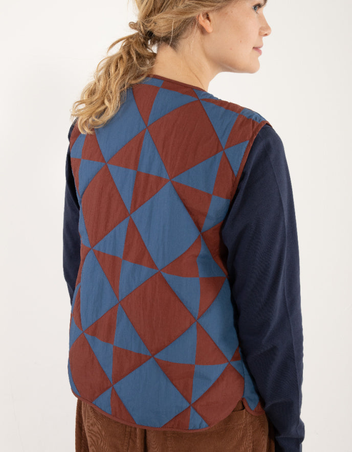 Person wearing a blue and red geometric patterned vest on a white background