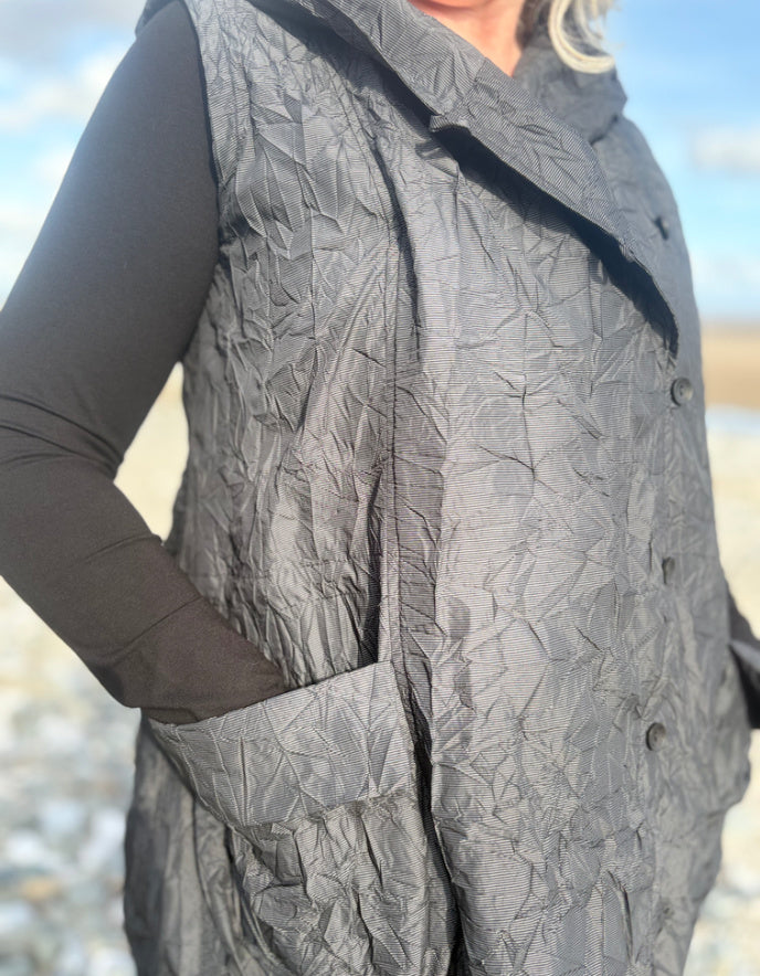 Person wearing a textured gray coat with a blurred natural background