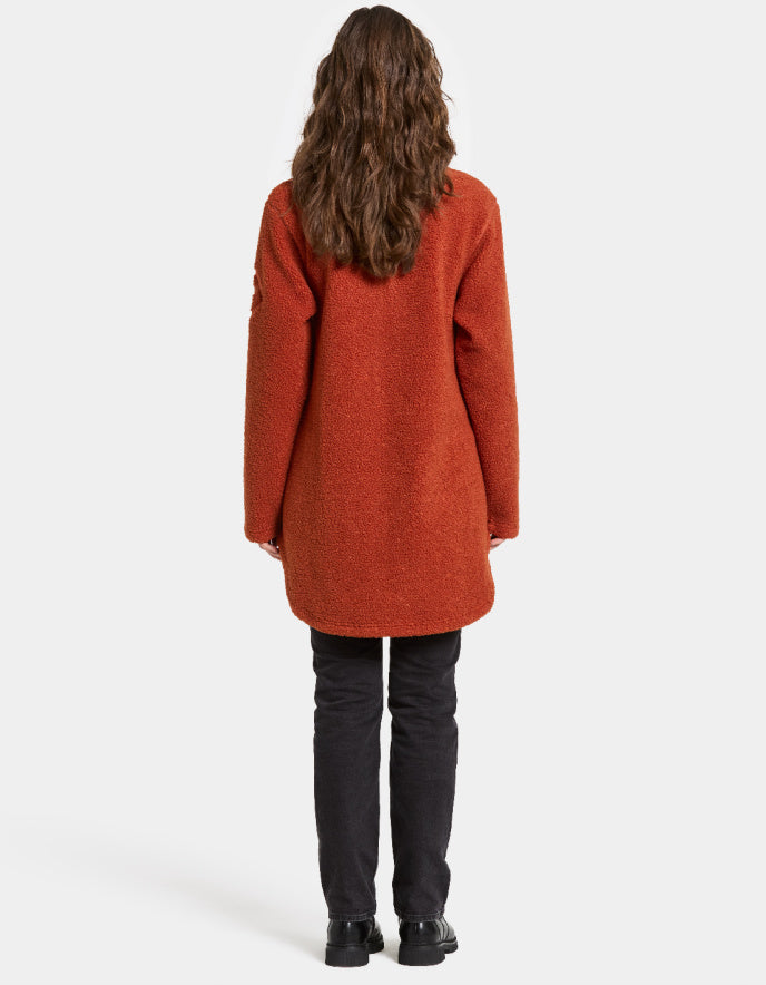 Woman wearing a rust orange sherpa pile fleece jacket on a white background