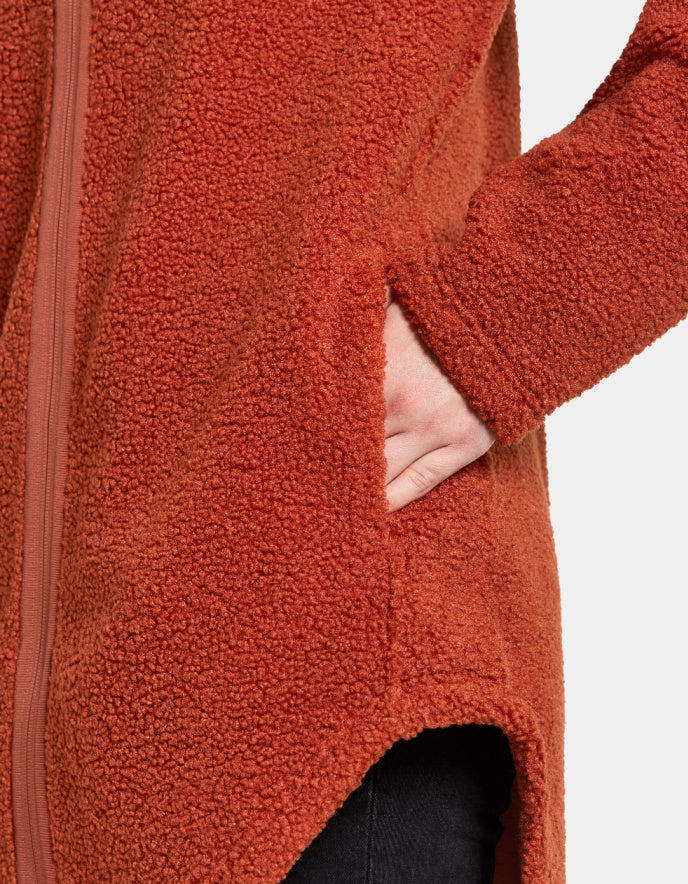 Woman wearing a rust orange sherpa pile fleece jacket on a white background