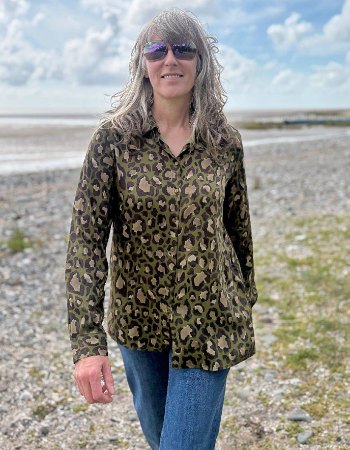 Person wearing a leopard print shirt on a pebbly beach