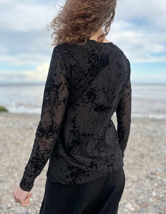 Person wearing a black distressed long-sleeve shirt on a beach