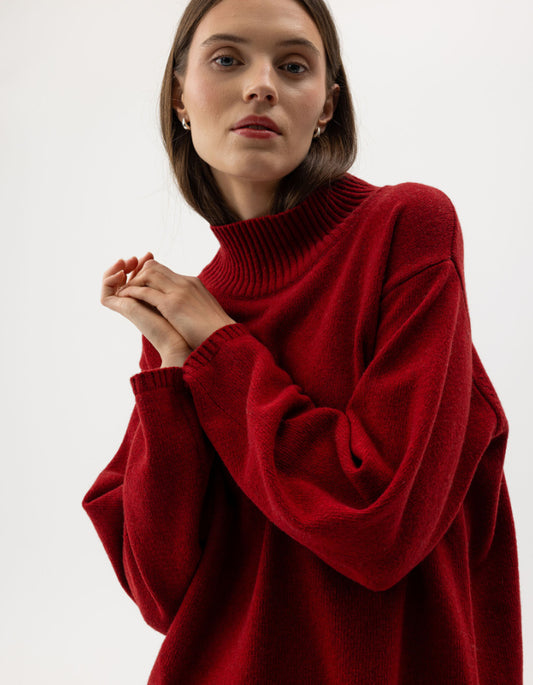 Woman wearing a red wool turtle neck sweater against a white background