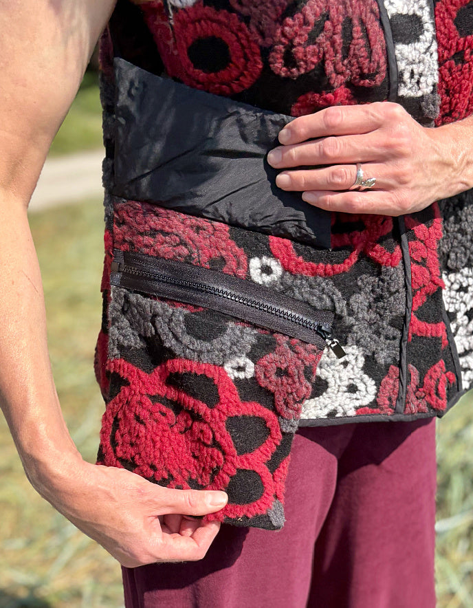 Woman wearing a floral patterned vest and burgundy pants standing in a field.