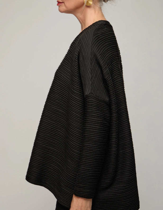 Black textured sweater worn by a person on a plain background