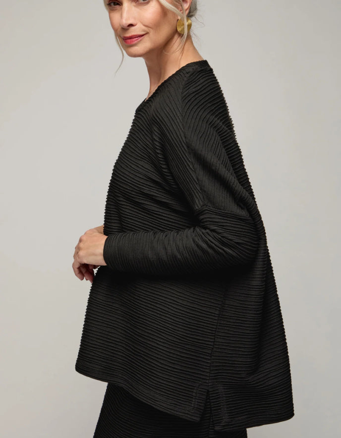 Woman wearing a black textured jacket against a plain background