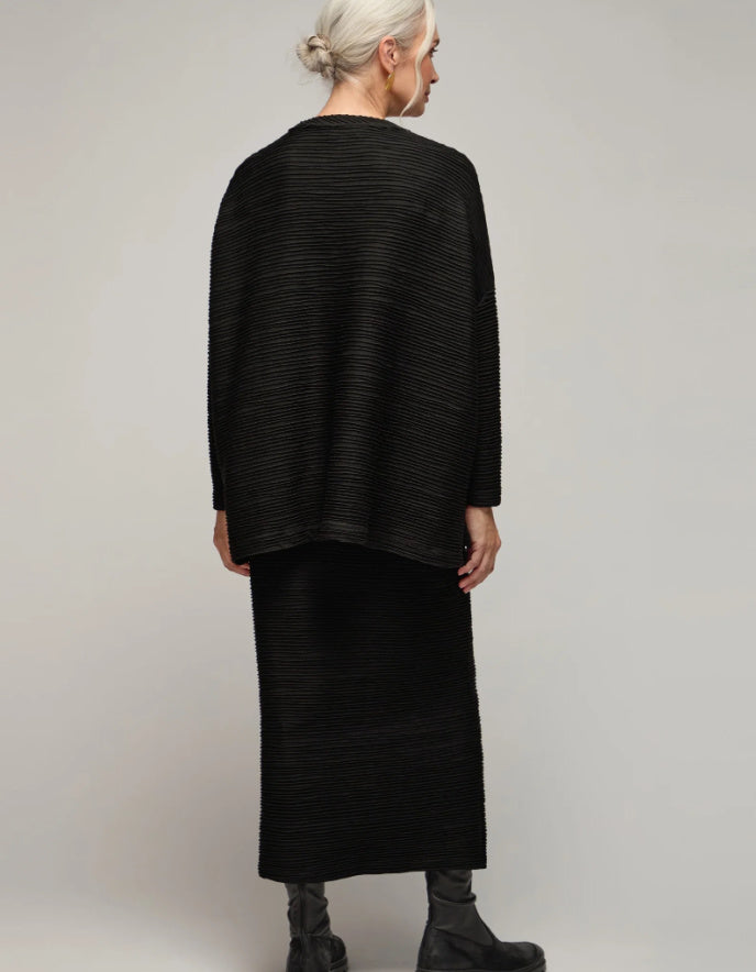 Person wearing a black textured outfit on a plain background