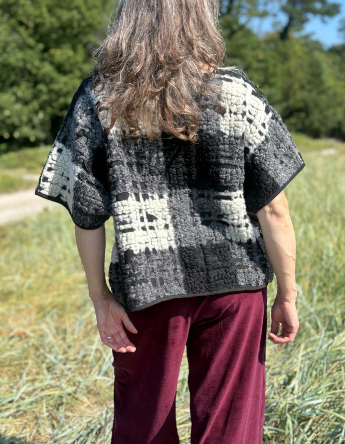 Person wearing a black and white patterned shirt in a grassy outdoor setting