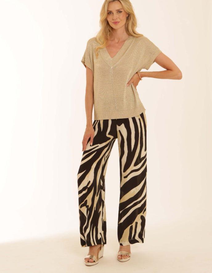 Woman wearing a beige top and zebra print pants on a white background