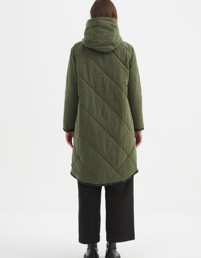 Person wearing a green quilted coat on a white background