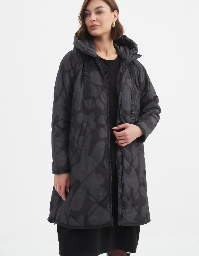 Woman wearing a long dark coat with a pattern on a white background