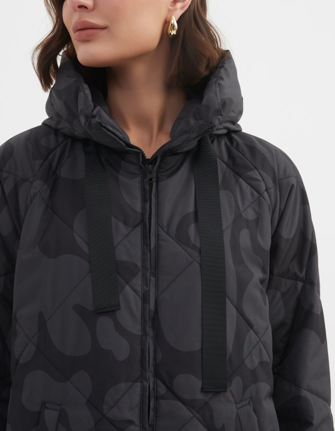 Person wearing a black quilted jacket with a pattern on a white background