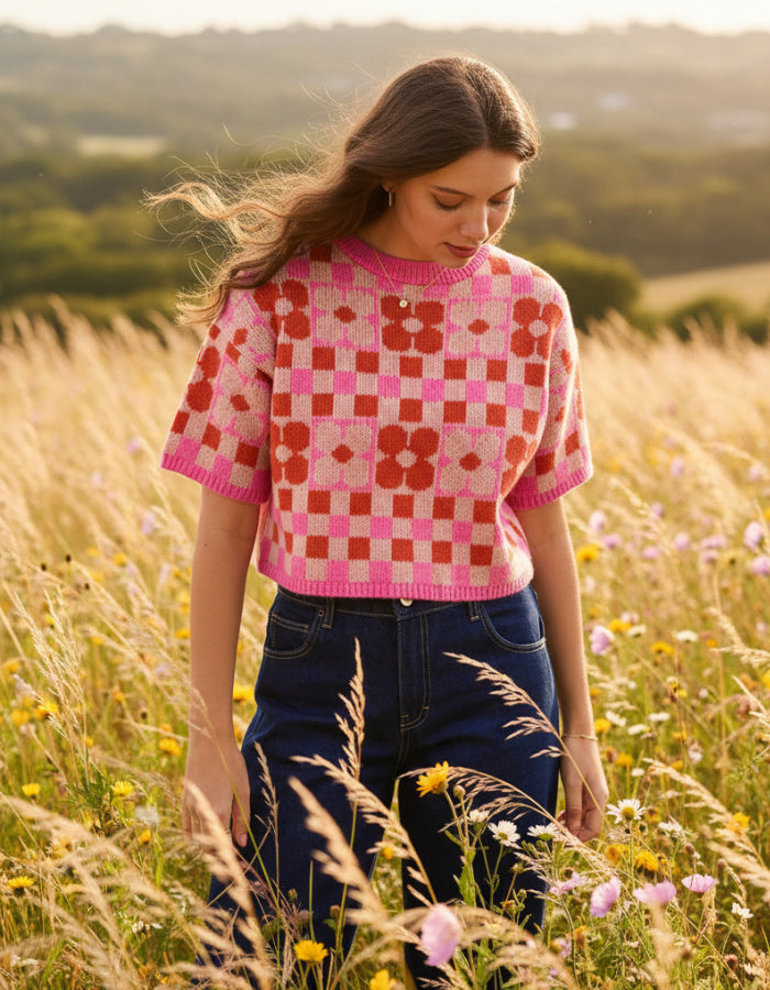 woman wearing a checkerboard and flower pink and red tank top sweater