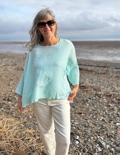 woman wearing loose fit mint top with cream jeans
