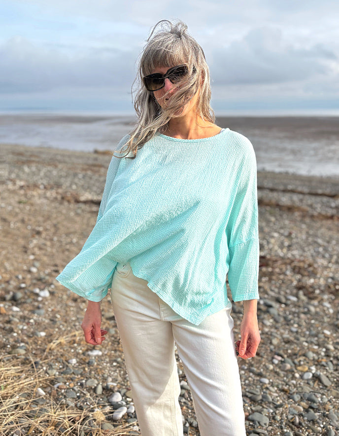 woman wearing loose fit mint top with cream jeans
