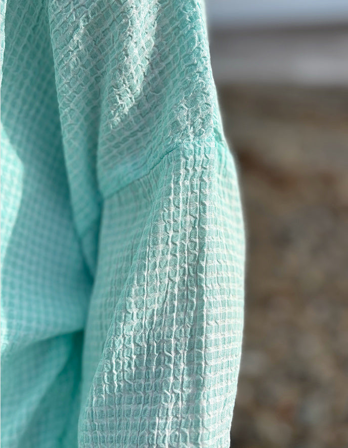 woman wearing loose fit mint top with cream jeans