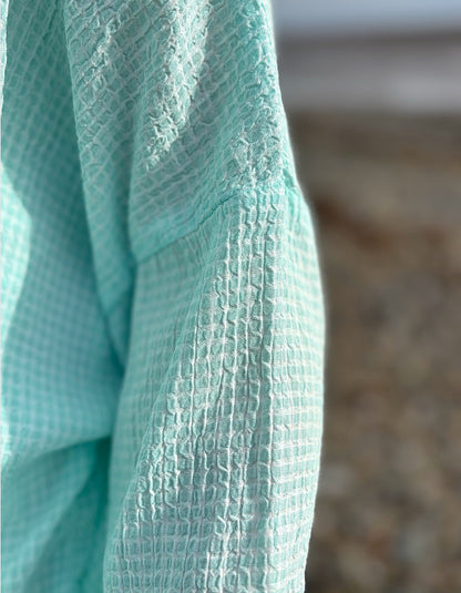 woman wearing loose fit mint top with cream jeans