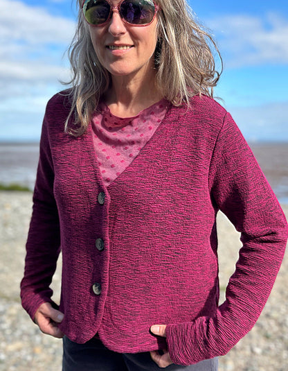 Woman wearing a pink cardigan over a pink top on a beach