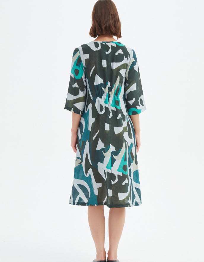 Woman wearing a patterned dress with abstract designs on a white background