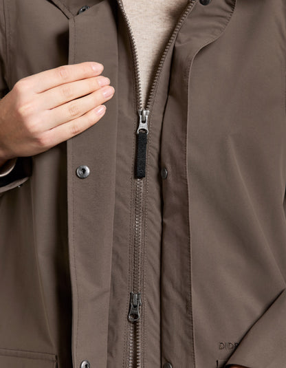 Close-up of a brown jacket with a zipper and button details.