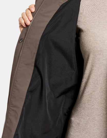 Close-up of a person wearing a beige jacket with a black lining, focusing on the zipper area.