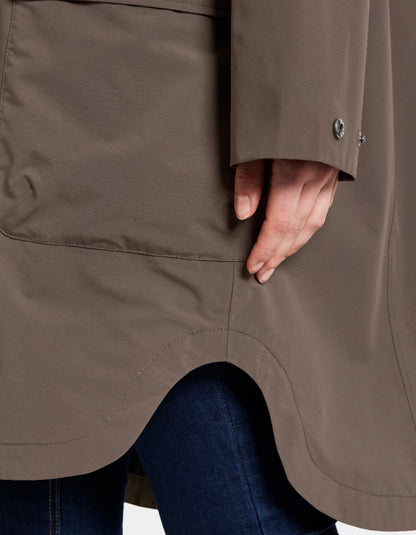 Close-up of a brown coat with a hand partially visible, wearing a blue garment underneath.