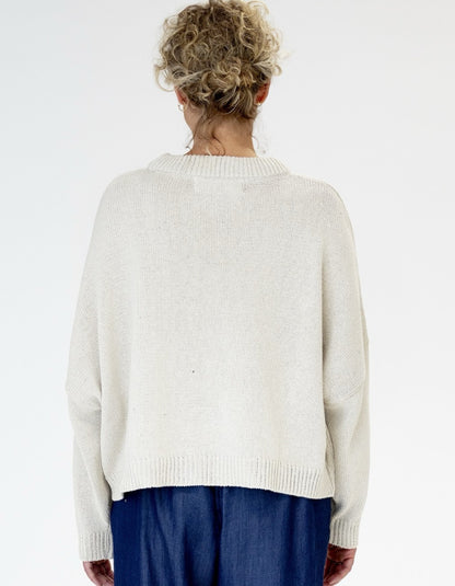 Person wearing a white sweater and blue pants on a white background