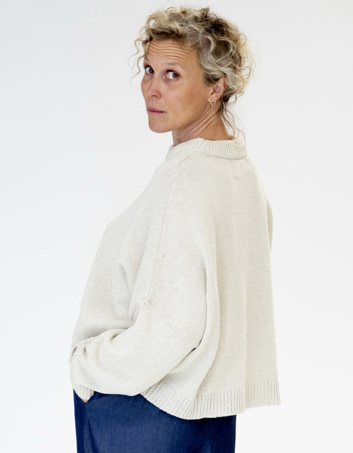 Woman wearing a white sweater against a plain background
